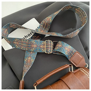 Detail view of retro ethnic geometric woven shoulder strap with gold metal buckle hardware