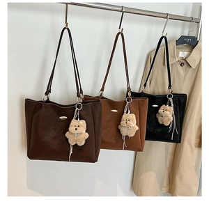 Detailed display of large matte leather tote bags in dark brown, caramel, and black with bear charms