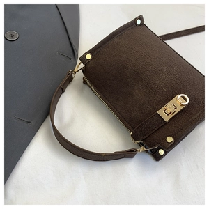 Close-up of retro dark brown shoulder bag with crackle texture and golden buckle clasp