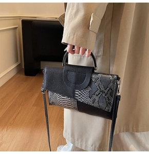 Nahaufnahme einer Handtasche mit Schlangenmuster, schwarzem Leder und Metallgriff