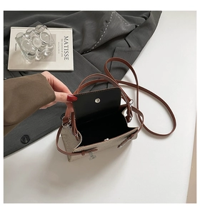 Detail of oat-colored woven crossbody bag showing leather strap and metal magnetic closure