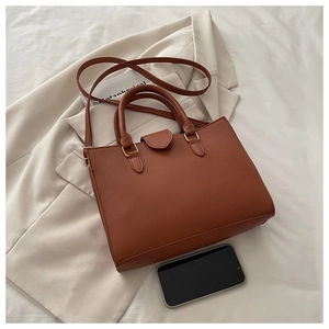 Macro shot of brown leather texture and gold hardware on retro tote bag with strap
