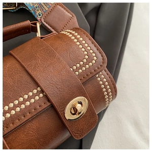 Detail of brown vintage Boston bag with ivory floral embroidery and gold metal clasp