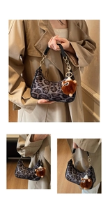 Detail of leopard print underarm bag with plush charm and gold chain decoration