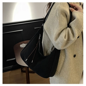 Detail of a large black vintage hobo bag with silver zipper and decorative brown cord