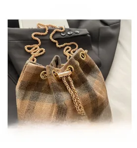 Detail of checkered bucket bag with tweed texture, gold chain and pearl drawstring charm