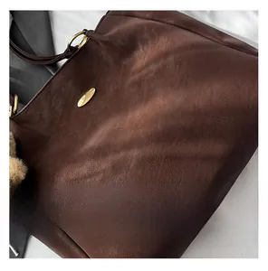 Close-up of brown tote bag with vintage leather texture and gold metal accents