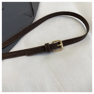 Close-up of adjustable dark brown textured leather shoulder strap with gold metal buckle