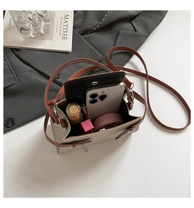 Detail view of the woven crossbody bag interior showing phone and cosmetics capacity