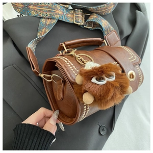 Detail of retro brown cylinder bag with gold rivets and bohemian patterned strap