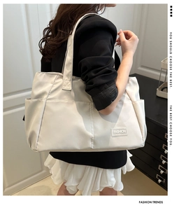 Vista laterale della grande borsa tote beige in nylon con tracolla larga e tasca laterale