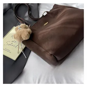Close-up of deep brown leather tote bag with grainy texture and golden metal emblem