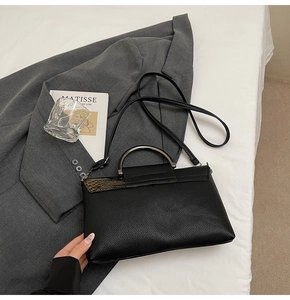 Detail der schwarzen Handtasche aus Leder mit Schlangenmuster und silbernem Ringgriff