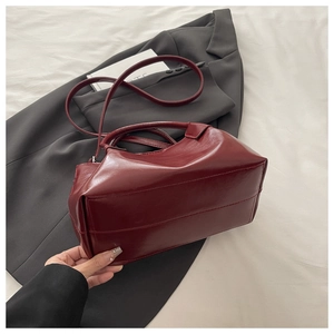 Gros plan d'un sac à main plissé rouge foncé avec poignée et bandoulière amovible