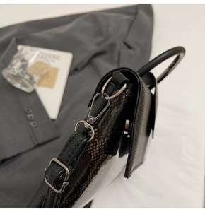 Detail der schwarzen Lederhandtasche mit Schlangenhaut-Seitenwand und silbernem Verschluss