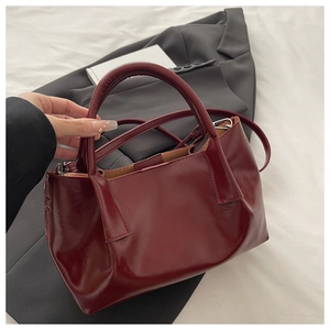 Vue de dessus d'un sac cabas bordeaux sur un blazer noir et une literie blanche