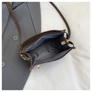 Detailed interior of a deep brown crossbody bag with gray lining and gold hardware zippers