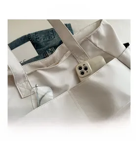 Dettaglio della borsa tote in nylon bianco con tasca esterna funzionale e cuciture rifinite