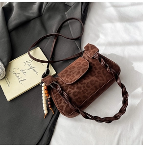 Detail of leopard print shoulder bag with braided strap and wooden bead pendant accessory