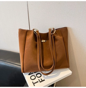 Detailed macro shot of vintage brown tote bag featuring premium leather texture and gold hardware