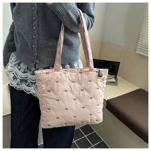 Dettaglio della borsa tote rosa trapuntata con ricami a fiocco e tracolla lunga