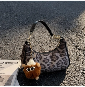 Detail of leopard print crescent bag with plush charm and golden chain straps