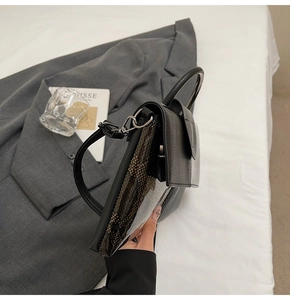 Detailansicht der schwarzen Tasche mit Schlangenhaut-Muster an der Seite und Griff