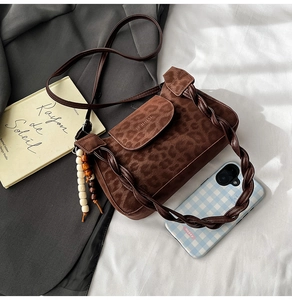 Close-up of leopard print shoulder bag with woven handle and wooden bead detail