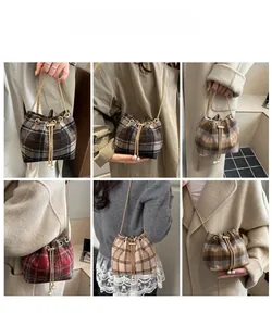 Detail view of stylish plaid wool bucket bags with gold chain straps on a model