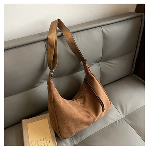 Detail of brown hobo bag in suede texture with adjustable strap and fringe tassel zipper