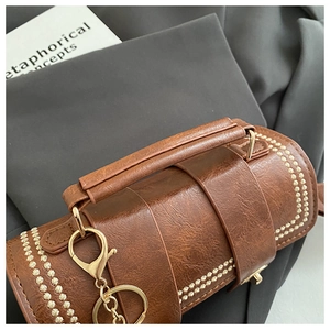 Close-up of retro brown Boston bag showing premium leather texture and gold floral rivets