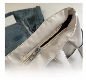 Dettaglio della cerniera argentata e delle cuciture su borsa tote in nylon bianco