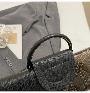 Detail der eleganten zweifarbigen Clutch mit schwarzem Narbenleder und braunem Schlangenmuster