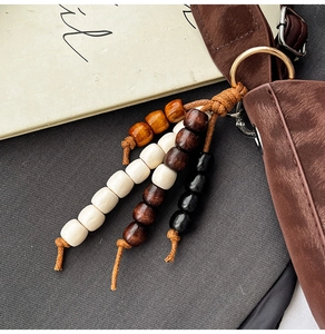 Close-up of colorful wooden bead keychain on a brown leather bag with a gold ring