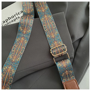 Close-up of bohemian geometric patterned wide strap with adjustable golden buckle