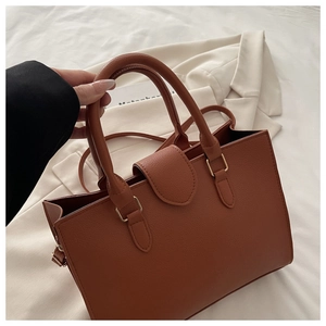 Close-up of caramel brown tote bag featuring pebbled texture and cylindrical handle