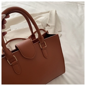 Close-up of brown lychee grain leather bag with gold hardware and elegant top handles
