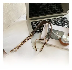Detail of dark brown leather tote with golden chain strap and large metal eyelets