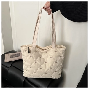 Dettaglio della borsa shopper trapuntata con ricamo a fiocco marrone e tessuto beige