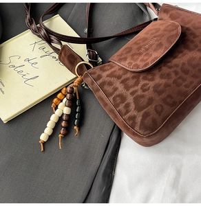 Close-up of leopard print suede shoulder bag with beaded ethnic fringe tassel and strap