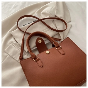 Detail of caramel brown litchi pattern leather bag with golden hardware and handles