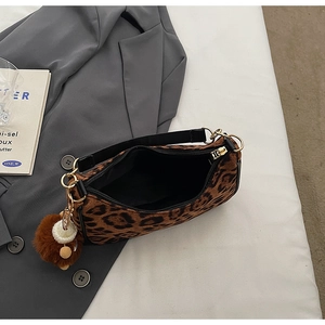 Close-up of leopard print shoulder bag with gold hardware and plush ball charm detail