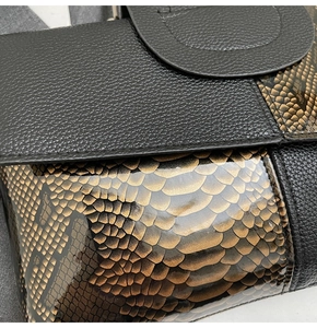 Detail aus schwarzem Litschi-Leder und bronze Schlangenleder-Textur an der Handtasche