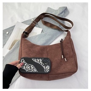 Detail view of large brown faux suede crescent bag with adjustable strap and zip tassel