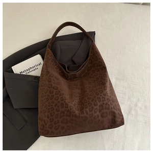 Flat lay macro view of the leopard print tote bag next to a grey suit and decorative books