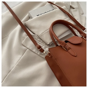 Detail of tan pebble leather tote bag with gold hardware and removable shoulder strap