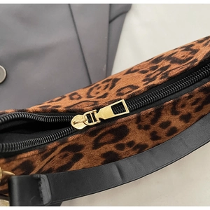 Detailed close-up of leopard print fabric texture and premium gold metal zipper on handbag