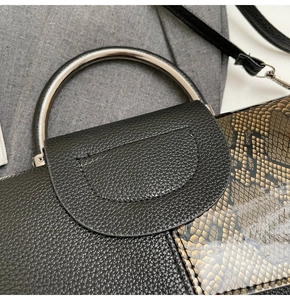 Nahaufnahme der schwarzen Lederhandtasche mit Schlangenmuster-Details und Silbergriff