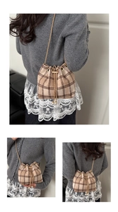 Detailed close-up of brown plaid tweed bucket bag with gold chain and pearl drawstring