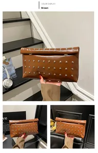 Close-up of brown leather envelope clutch bag with silver rivet studs and magnetic snap